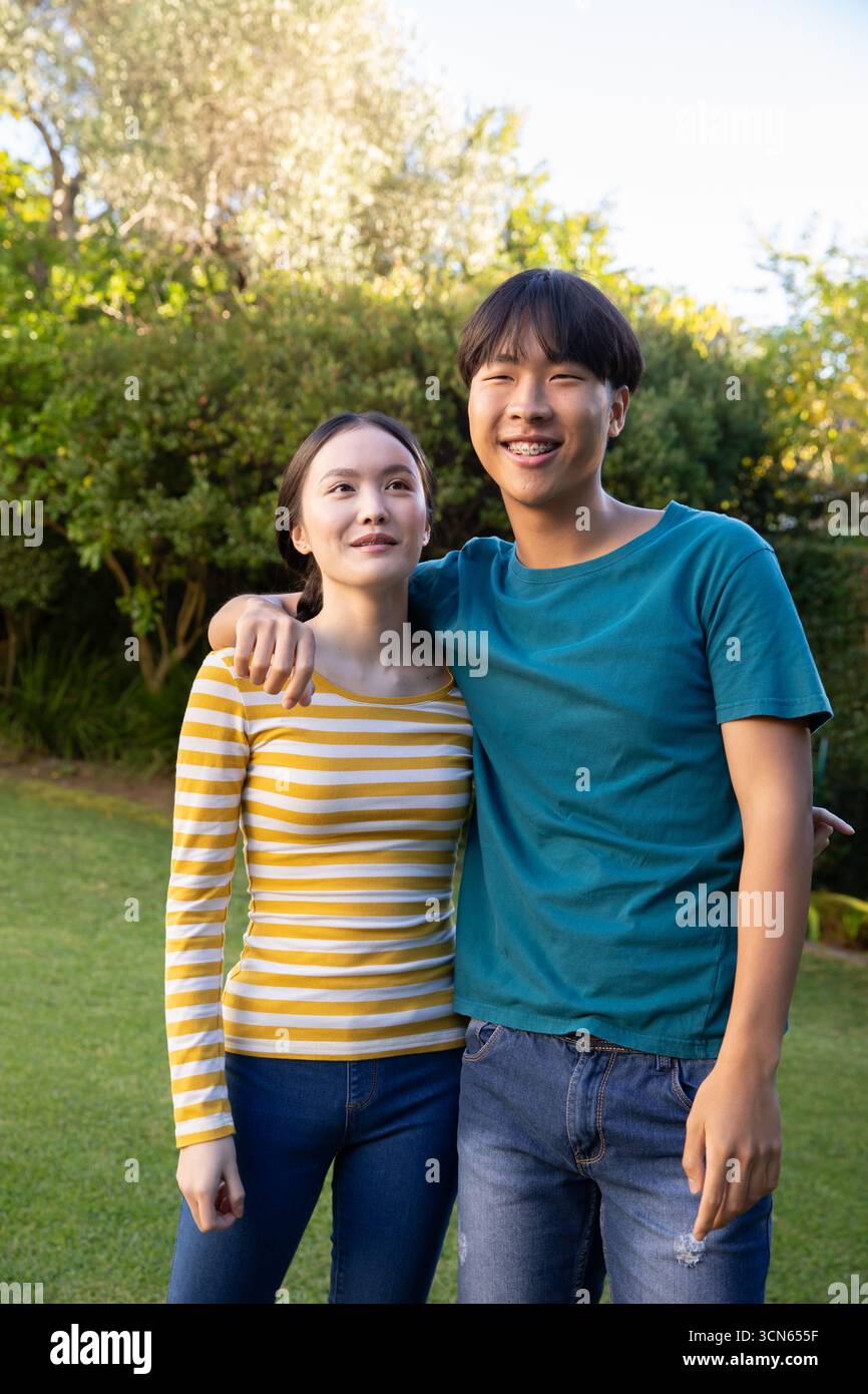 Couple asiatique debout sur la pelouse verte dans le jardin arrière sous la lumière du soleil Banque D'Images
