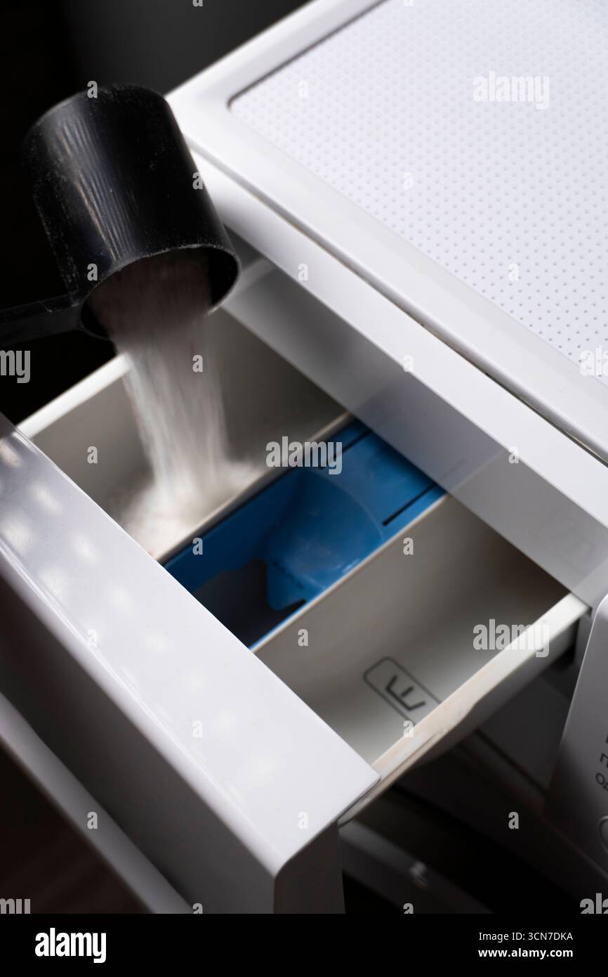 Gros plan de la poudre de détergent à lessive blanche versée dans un tiroir de machine à laver. Utile pour les sujets relatifs au nettoyage, aux tâches ménagères ou au nettoyage Banque D'Images
