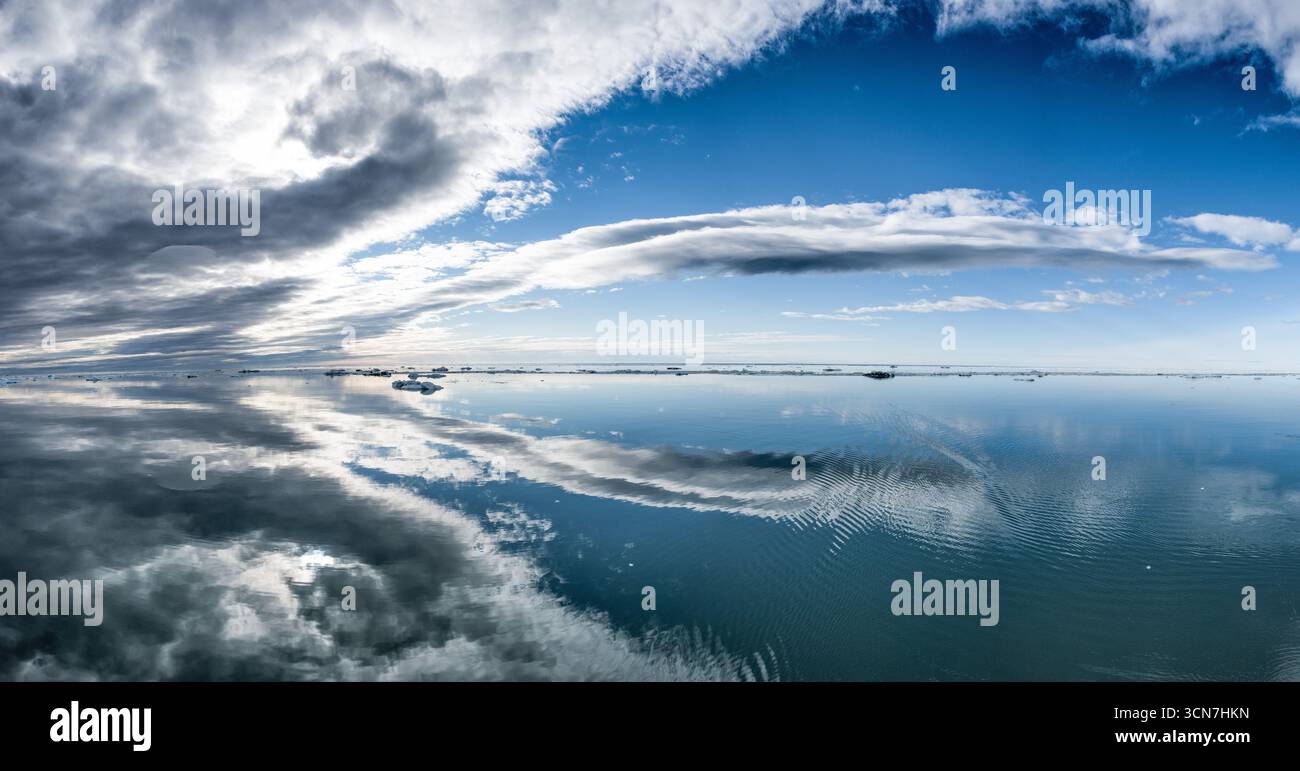 Klerckbukta Nordaustlandet Svalbard Mer arctique | NORDAUSTLANDET, Svalbard — Des plaques de glace dispersées dérivent sur les eaux miroirs et calmes de Klerckbukta, une baie sur la côte sud-est de Nordaustlandet où le dôme de glace d’Austfonna rencontre la mer de Barents. Nordaustlandet est entièrement inhabitée, plus des trois quarts de sa surface sont recouverts de glace, et elle se trouve entièrement dans la réserve naturelle de Nordaust-Svalbard, la plus grande zone protégée de Norvège avec 55 354 kilomètres carrés (21 372 milles carrés). La baie n’est accessible que pendant la brève fenêtre de la fin de l’été lorsque la banquise se retire. Banque D'Images