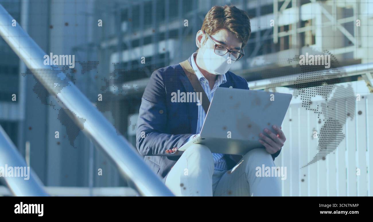 Homme asiatique travaillant dans le blazer marine tapant sur ordinateur portable sur la terrasse extérieure, avec sac en cuir-bracelet Banque D'Images