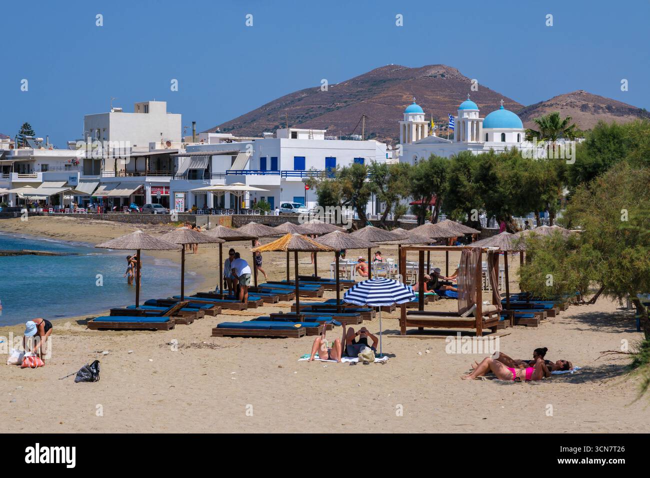 Parikia, Paros, GR - 22 août 2025 : les gens prennent le soleil sur la plage de Parikia, en profitant du sable et de la mer Banque D'Images