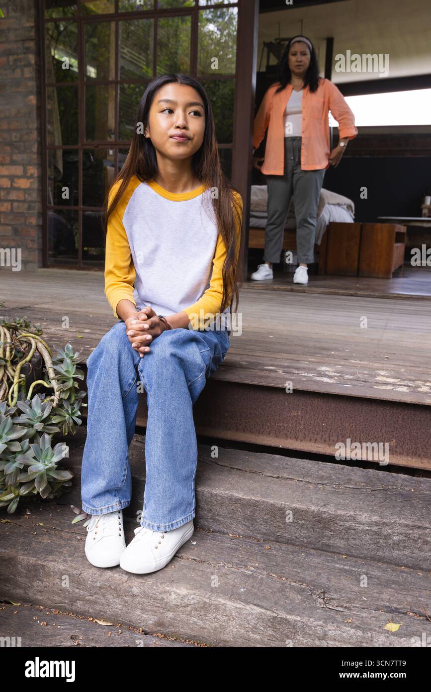 Mère asiatique et fille interagissant à la maison à travers les portes vitrées des marches du porche avec des succulentes Banque D'Images