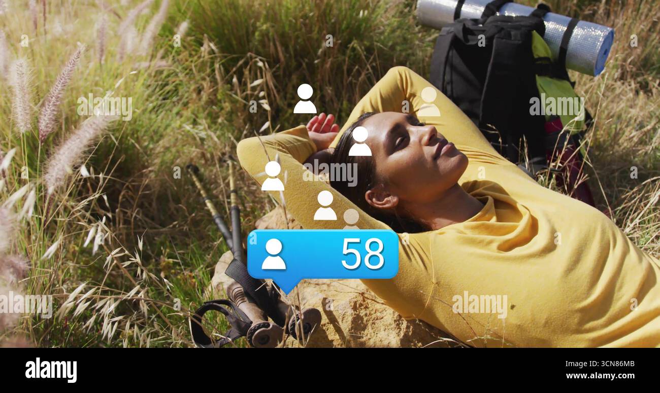 Randonneur inclinable en haut jaune sur rocher dans la prairie, avec sac à dos, bâtons de randonnée, bulle de notification Banque D'Images