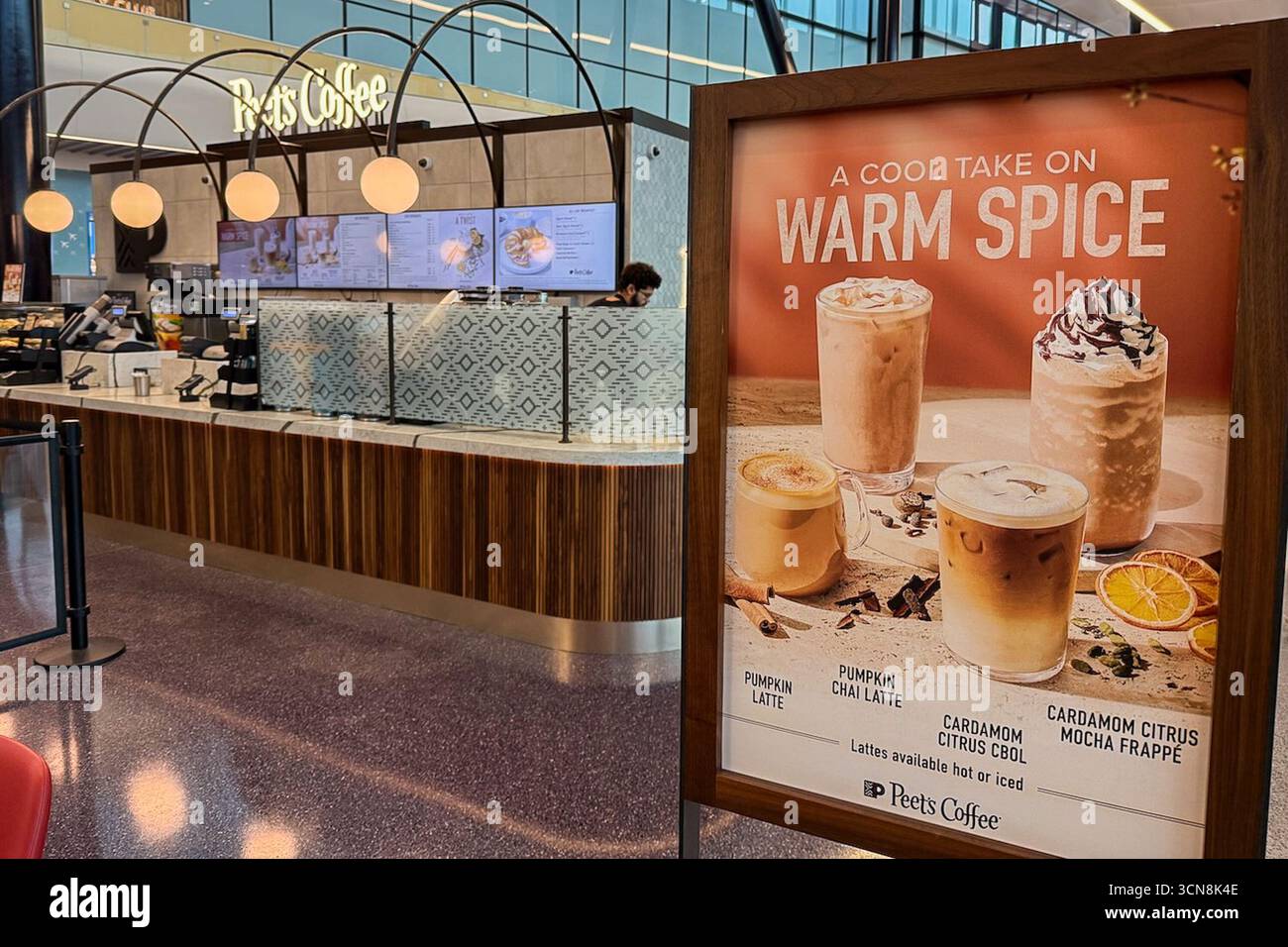 East Boston, États-Unis. 01 Sep, 2025. 1er septembre 2025 Un comptoir Peet's est visible à l'intérieur d'un terminal de l'aéroport international Boston Logan, avec un affichage promotionnel de premier plan présentant une offre de boissons « CHAUDES ÉPICES ». Le comptoir a une finition en bois clair et une rangée de suspensions au-dessus. Une grande publicité sur pied présente des boissons glacées et chaudes avec des tranches d'orange et des garnitures fouettées. Crédit : Sipa USA/Alamy Live News Banque D'Images