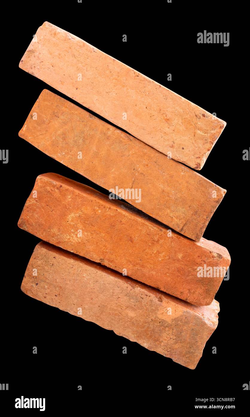 Vue latérale de quatre vieilles briques rouges ou oranges fissurées dans la pile est isolée sur fond noir avec chemin de détourage. Banque D'Images