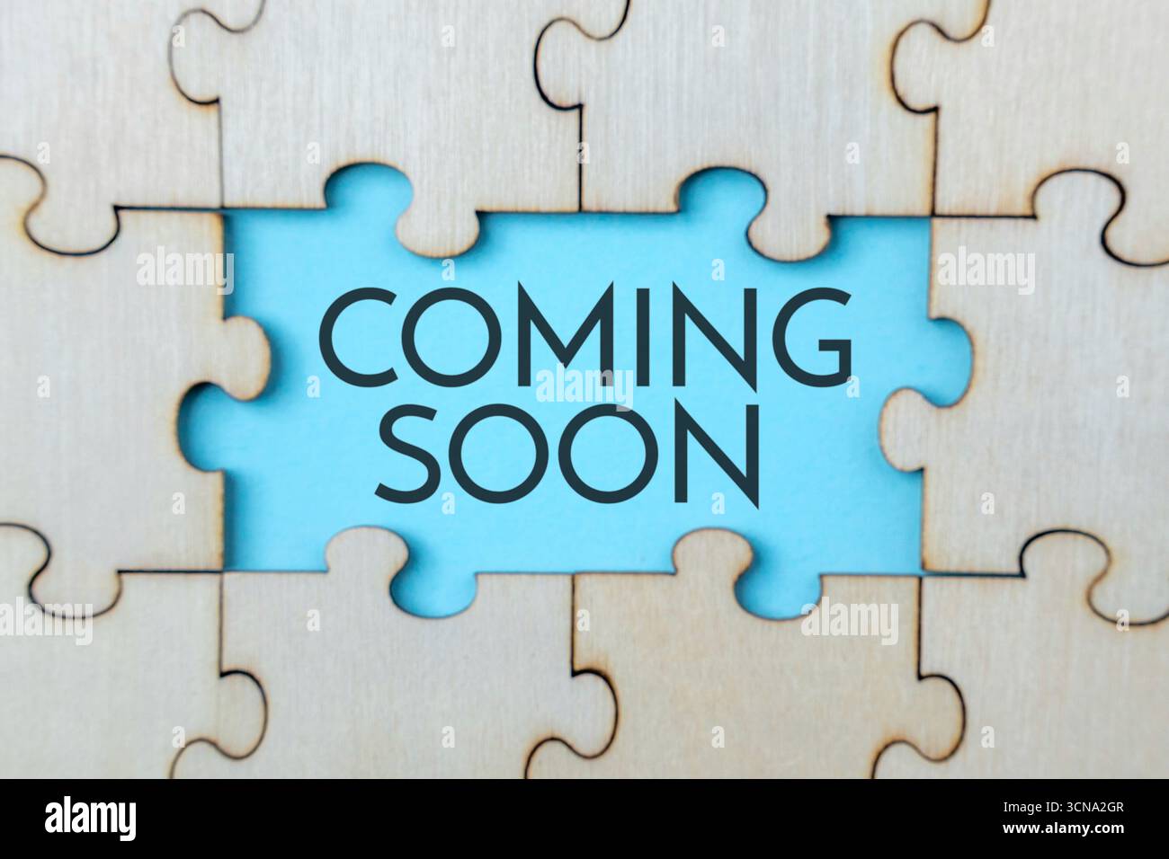 Un puzzle en bois avec une pièce manquante, révélant un fond bleu avec le texte 'COMING SOON'. Événement à venir, sortie de produit, annonces ou promo Banque D'Images Un puzzle en bois avec une pièce manquante, révélant un fond bleu avec le texte 'COMING SOON'. Événement à venir, sortie de produit, annonces ou promo Banque D'Images