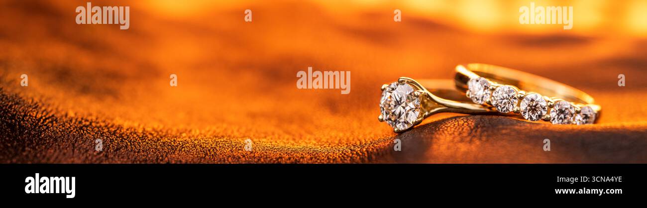 Une bague en or et diamant est sur un morceau de tissu. Le tissu est de couleur orange. L'anneau est placé sur le tissu de telle sorte qu'il ressemble à R Banque D'Images