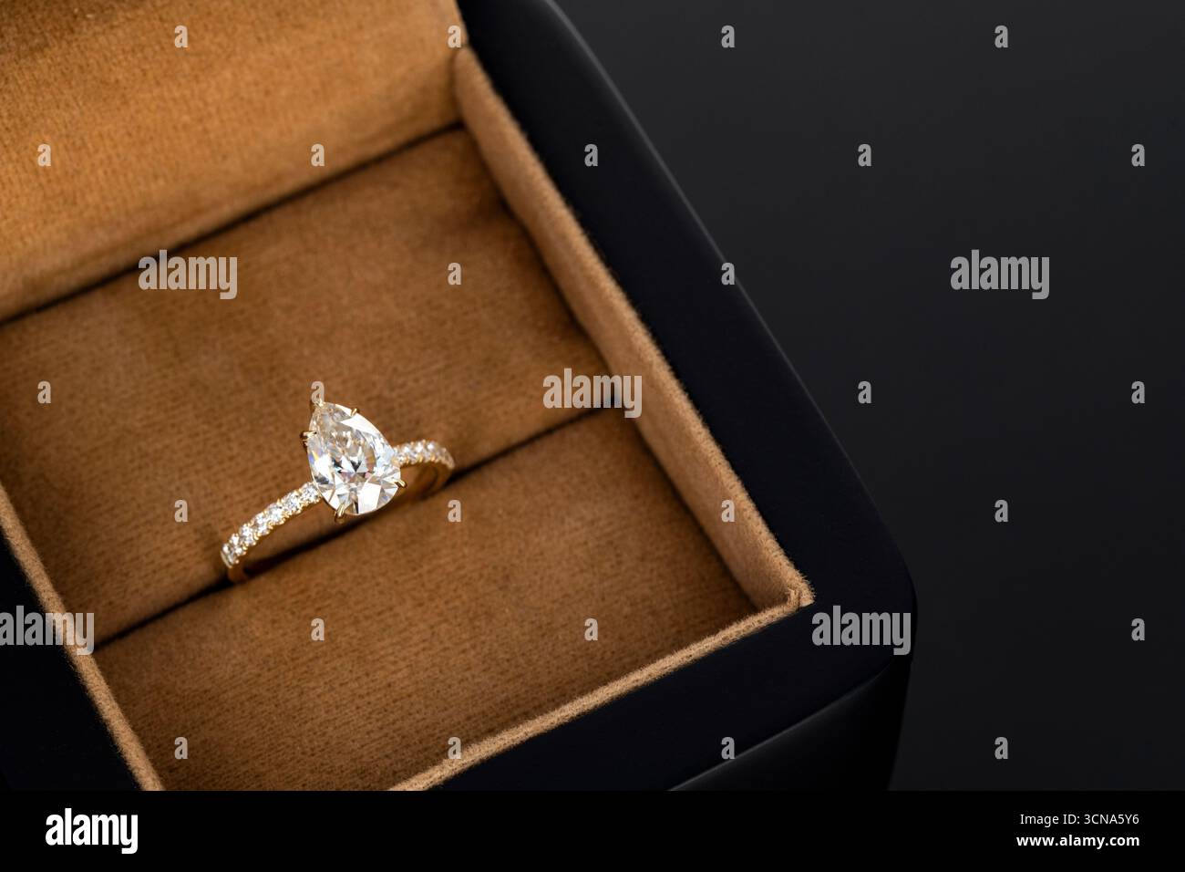 Une bague en diamant or et blanc est dans une boîte. La boîte est brune et a une garniture dorée Banque D'Images