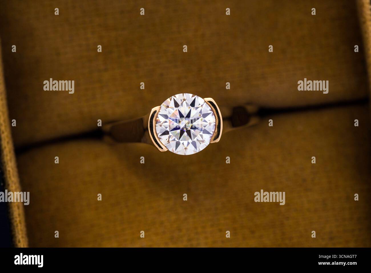 Une bague en diamant or et blanc est affichée dans une boîte. L'anneau est le centre d'attention et est entouré d'un tissu jaune. L'anneau est un symbole de Banque D'Images
