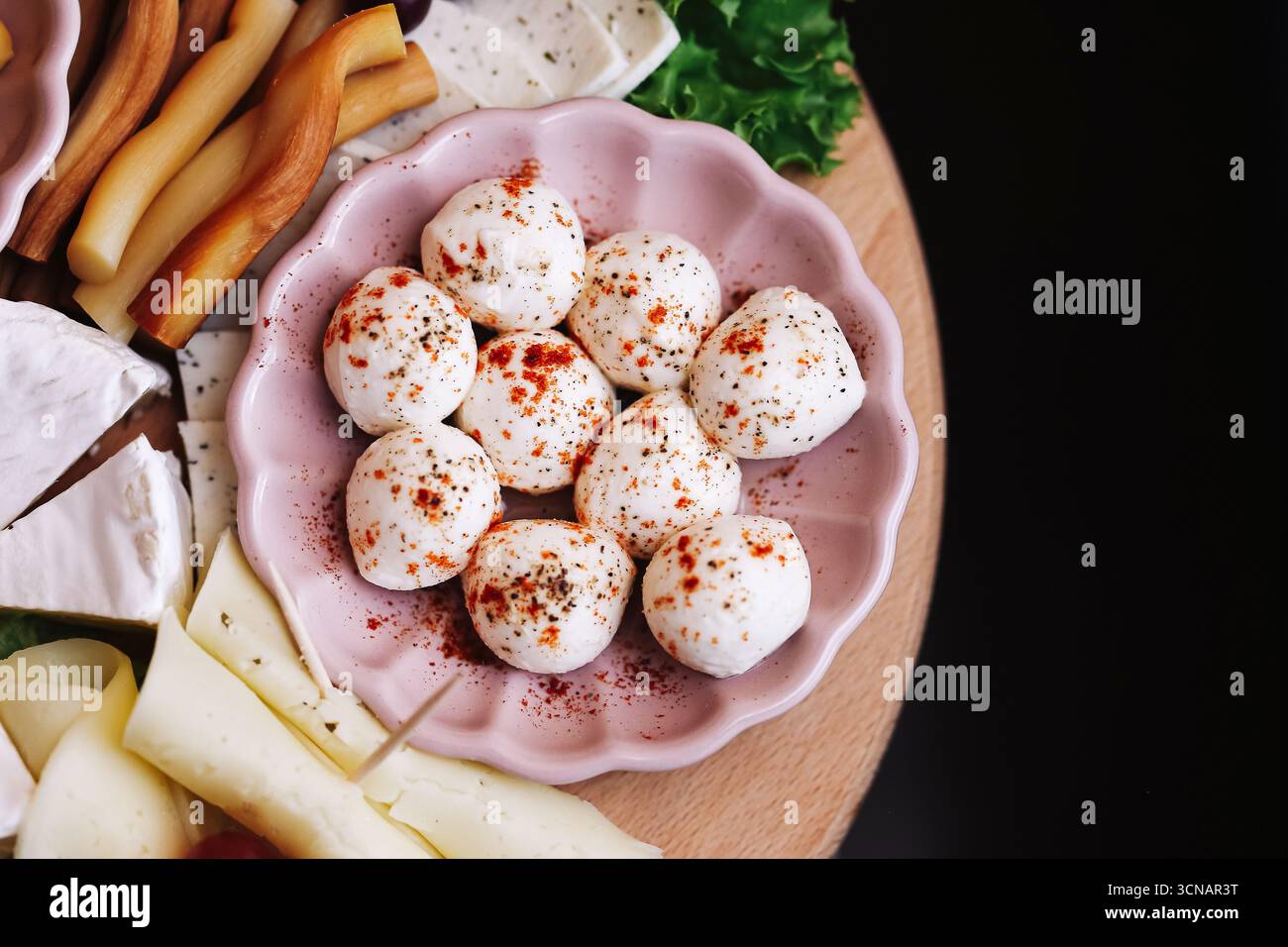 Boules de fromage apéritif avec épices. Mozzarella fraîche dans un bol avec des herbes. En-cas laitier traditionnel servi avec assortiment de fromages. Gourment délicieux. Banque D'Images