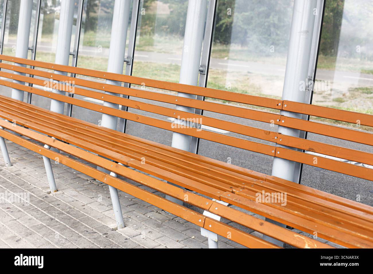 Bancs en bois à l'arrêt de bus. Longue rangée de sièges dans un abri moderne. Conception des transports publics et des infrastructures urbaines. Banque D'Images