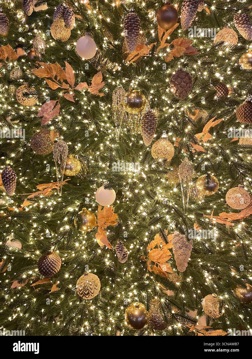Arbre de Noël brillant de luxe avec boules métalliques dorées et transparentes, pommes de pin, feuilles et guirlande lumineuse. Motif de vacances de Noël. Tendance et créati Banque D'Images