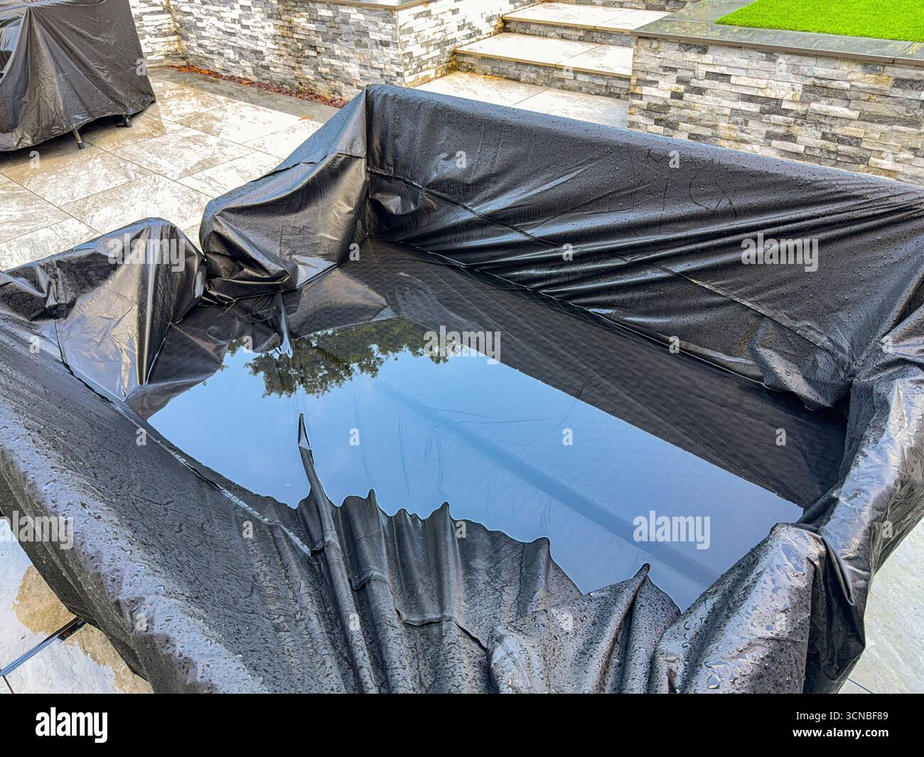 Eau se tenant sur la couverture des canapés de jardin après de fortes pluies d'une tempête. Personne. Banque D'Images