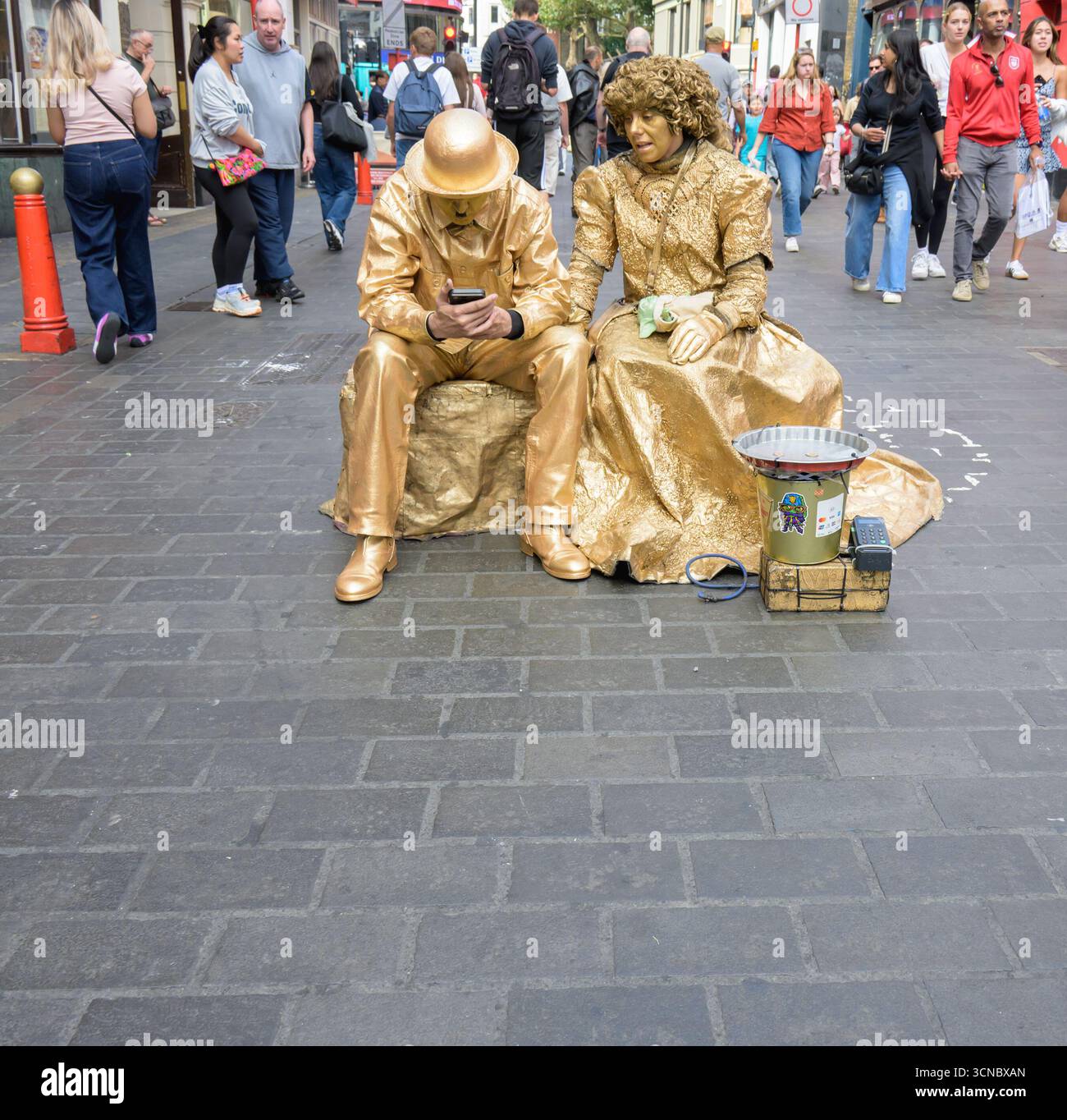 Londres, Royaume-Uni. Deux statues humaines ont une pause dans Chinatown Banque D'Images