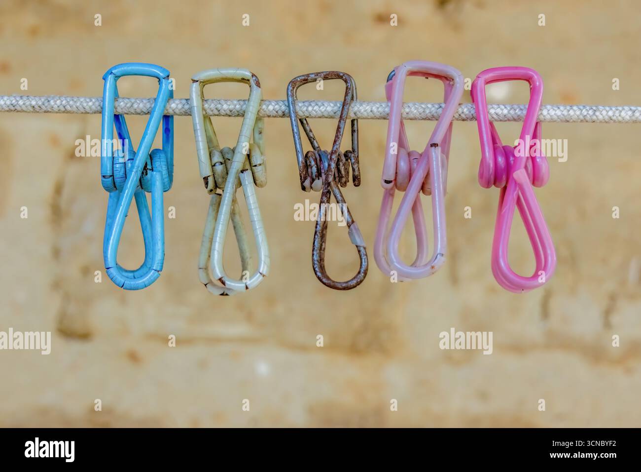 Vieille pince à linge en métal coloré altéré recouverte de plastique, suspendue à un cordon contre un mur d'adobe, dans une maison de ferme dans les montagnes andines orientales Banque D'Images