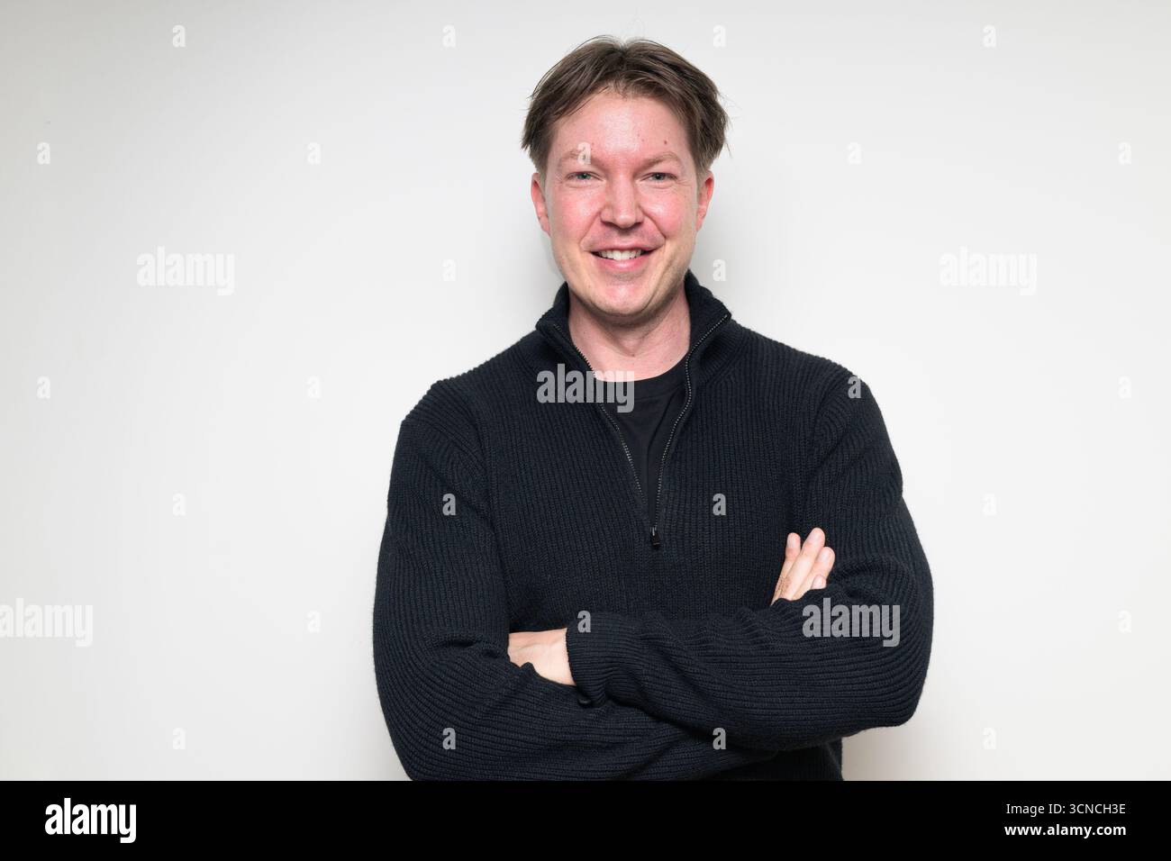 Homme scandinave mi-adulte souriant dans un portrait de pull noir sur fond blanc de studio Banque D'Images