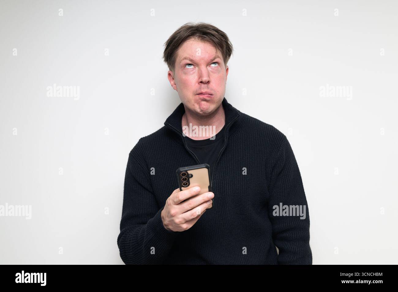 Portrait de studio de l'homme adulte moyen scandinave ennuyé à l'aide du téléphone sur fond blanc Banque D'Images