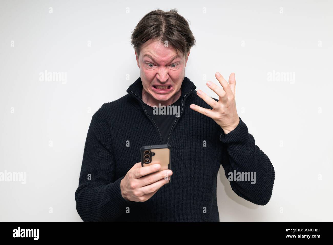 Portrait de studio de l'homme mi-adulte scandinave en colère à l'aide du téléphone sur fond blanc Banque D'Images