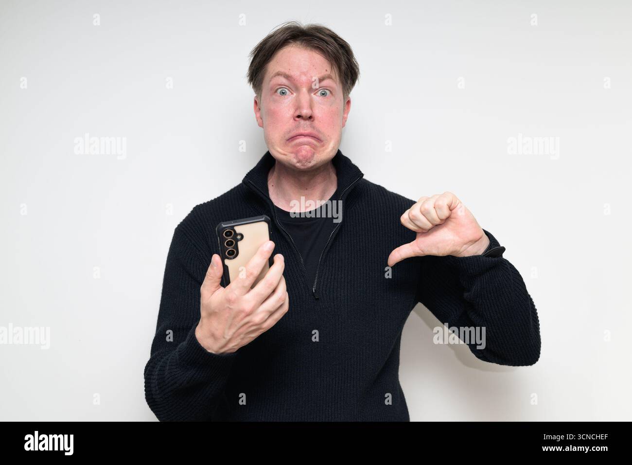 Portrait de studio de l'homme moyen adulte scandinave triste à l'aide du téléphone sur fond blanc Banque D'Images