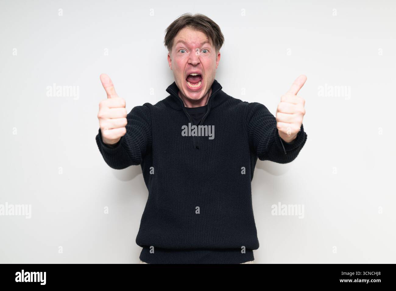 Homme scandinave mi-adulte souriant dans le portrait de pull noir sur fond blanc de studio donnant le pouce vers le haut geste Banque D'Images