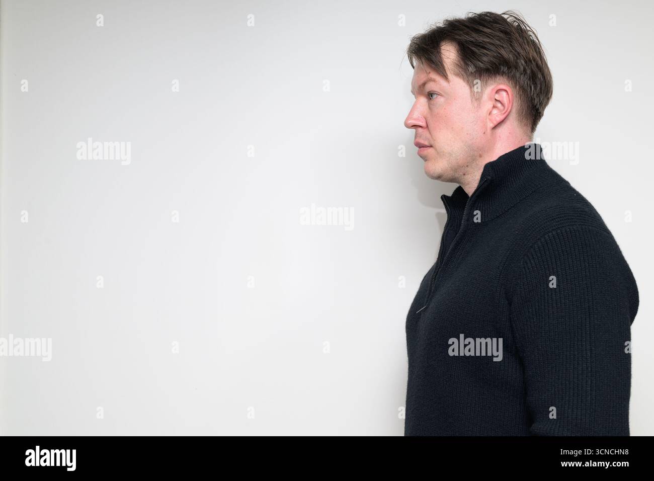 Vue de profil de l'homme adulte moyen scandinave en portrait de pull noir sur fond blanc de studio Banque D'Images