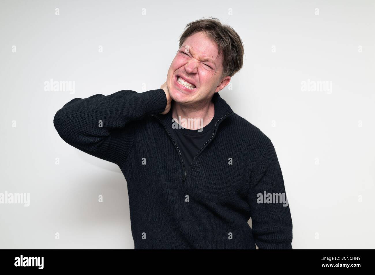Homme adulte scandinave moyen en pull noir ayant portrait de neckache sur fond blanc de studio Banque D'Images