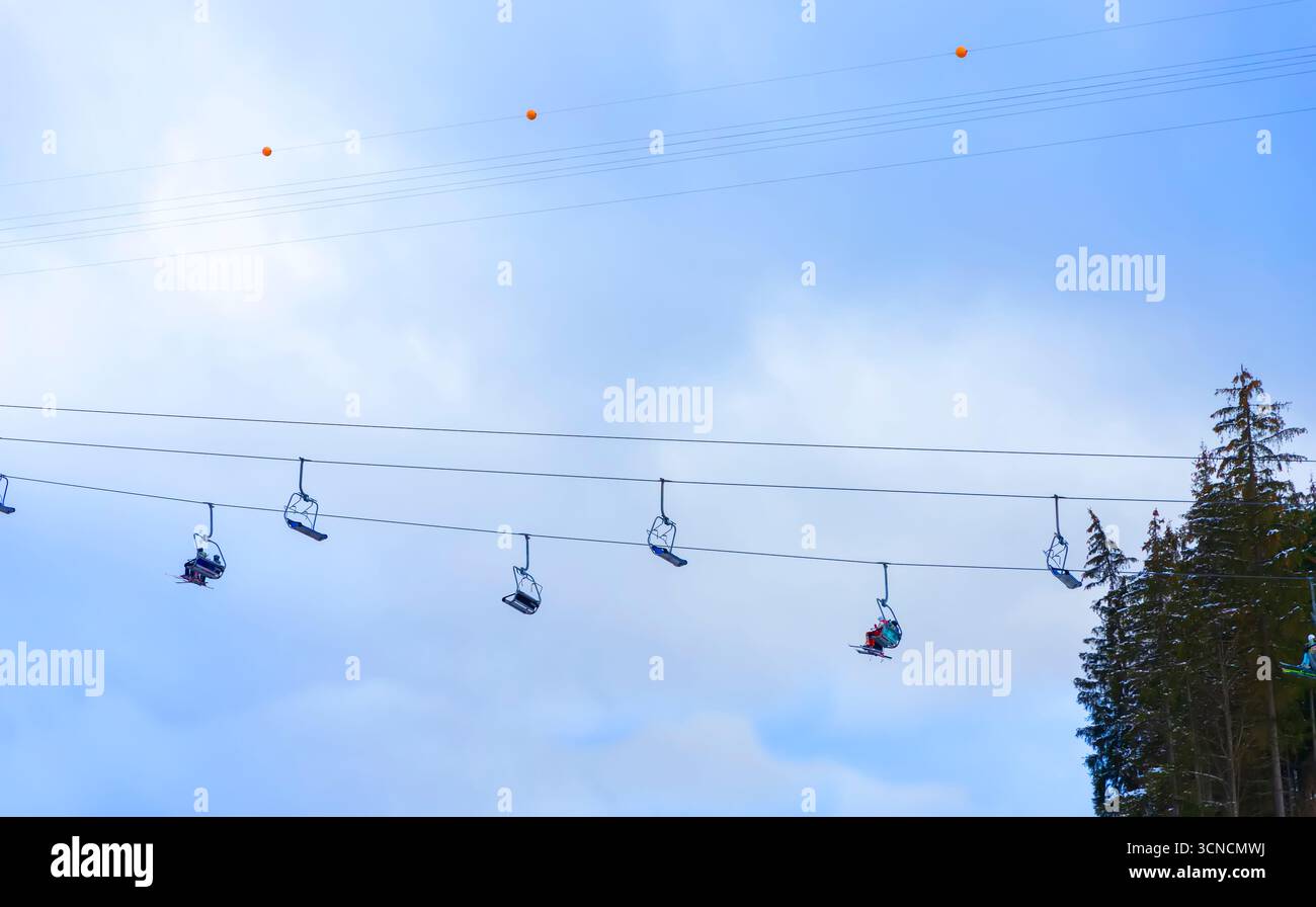 Vue sur les remontées mécaniques. Les gens en équipement de ski montent la montagne pour le ski et le snowboard. Vue de dessous. Chaises de téléski contre le ciel. Bukovel ski R Banque D'Images