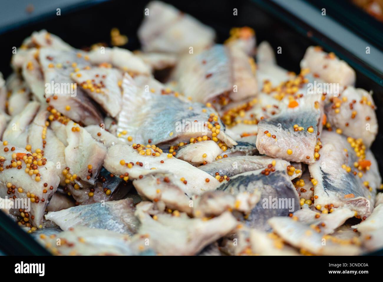 Gros plan de filets de hareng marinés avec graines de moutarde. Plat traditionnel de poisson mariné souvent servi comme apéritif ou en-cas dans la cuisine européenne Banque D'Images