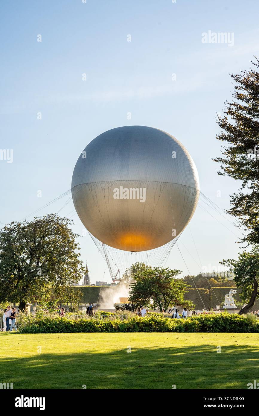 Chaudron olympique surmonté d'une montgolfière au jardin des Tuileries avec des touristes autour, lors de la célébration des Jeux Olympiques d'été de Paris 2024, Paris France Banque D'Images