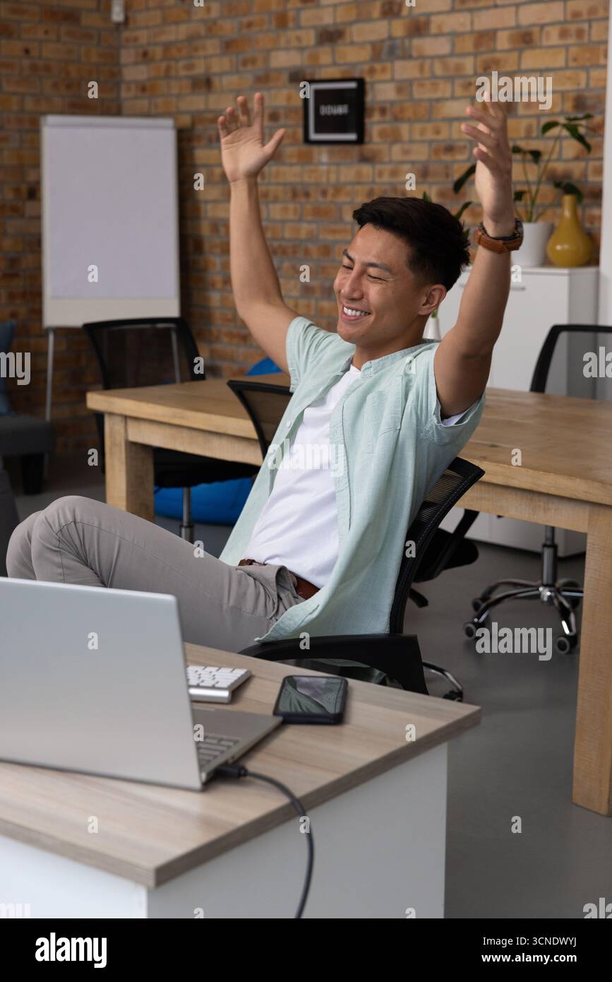 Homme asiatique étirant les bras au-dessus de la tête au bureau dans le bureau avec tableau de conférence pour smartphone portable Banque D'Images