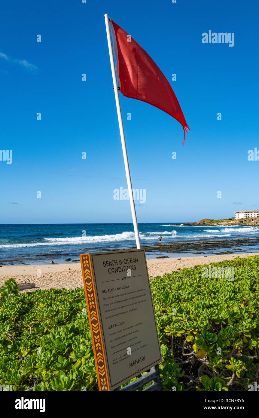Panneau d'information sur les conditions océaniques et drapeau d'avertissement rouge signalant les conditions océaniques dangereuses à Shipwreck Beach, dans la région de Poipu à Kauai, Hawaii, Banque D'Images