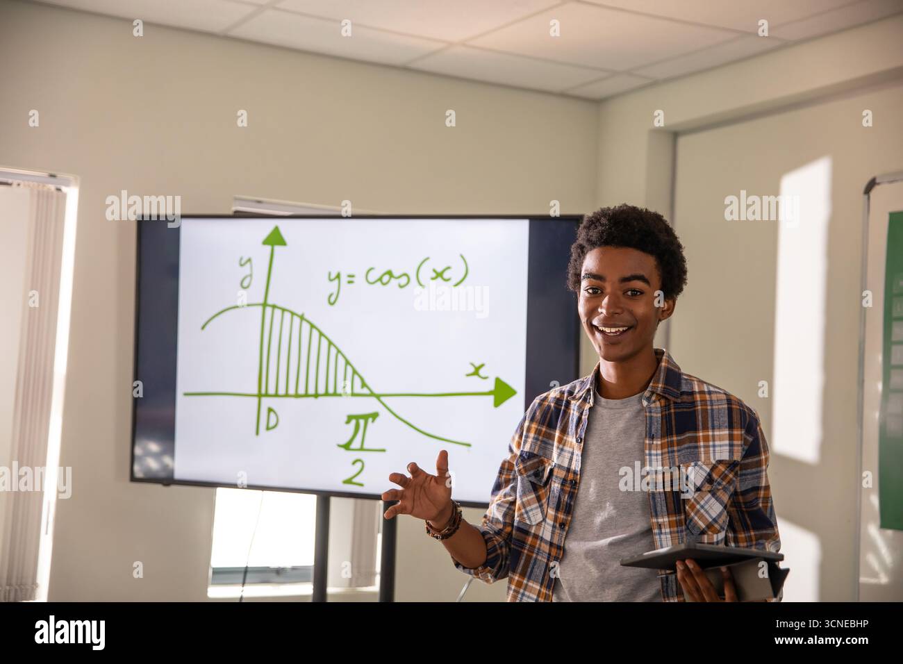 Homme afro-américain faisant des gestes à l'écran montrant une courbe cosinus, tenant la tablette en classe, copiez l'espace Banque D'Images