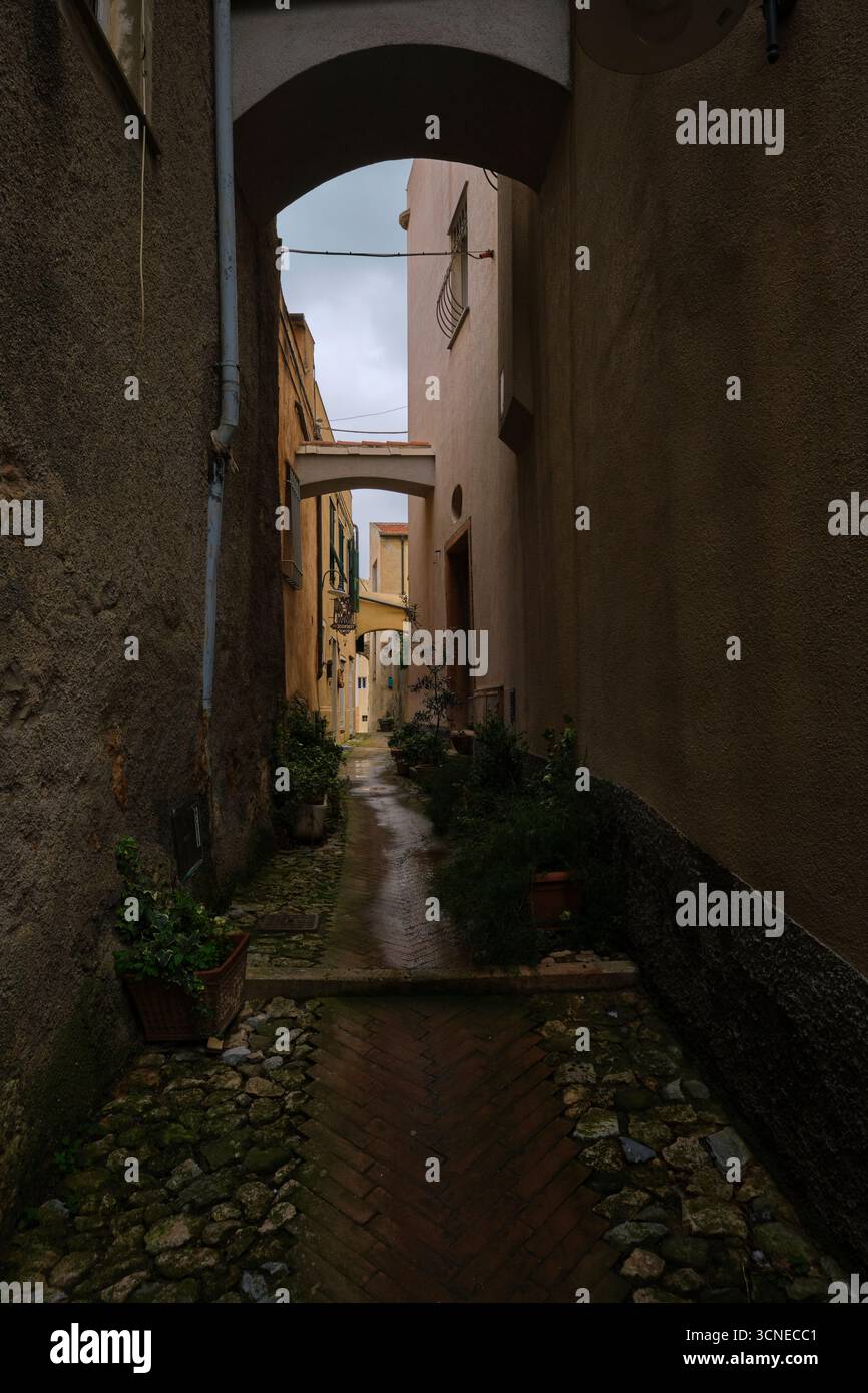 Vue en bas d'une voie de marche, voûtée sur une journée grise, pluvieuse et humide. Romantique avec pavés. Dans le village rural de Borgio Verezzi. En Ligurie, Italie. Banque D'Images