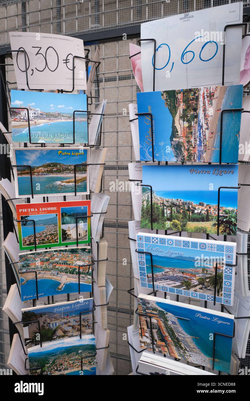 Diverses photos de cartes postales en couleur à vendre sur un rack dans un magasin de souvenirs. Dans la ville balnéaire de Pietra Ligure, Ligurie, Italie. Banque D'Images