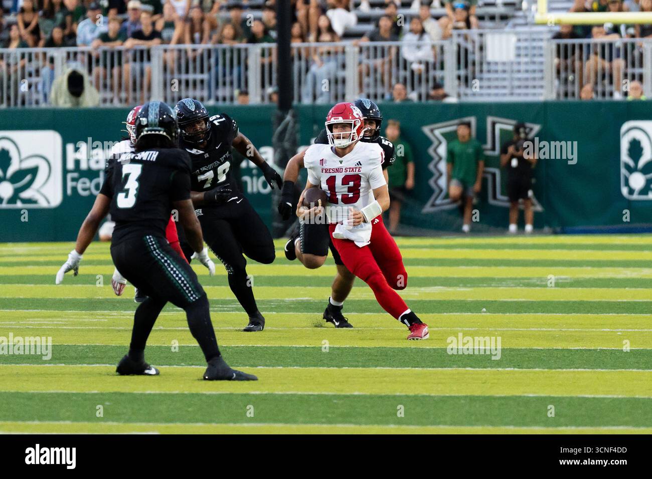 Honolulu, Hawaï, 20 septembre 2025. (L) le quarterback #13 E.J. Warner de Fresno State remet la main à (R) le Runback #2 Rayshon Luke dans Mountain West Open Play et la victoire 23 à 21 des Bulldogs sur les Warriors de l'Université de Hawai'i. Crédit : Solomon Thompson/Alamy Live News Banque D'Images