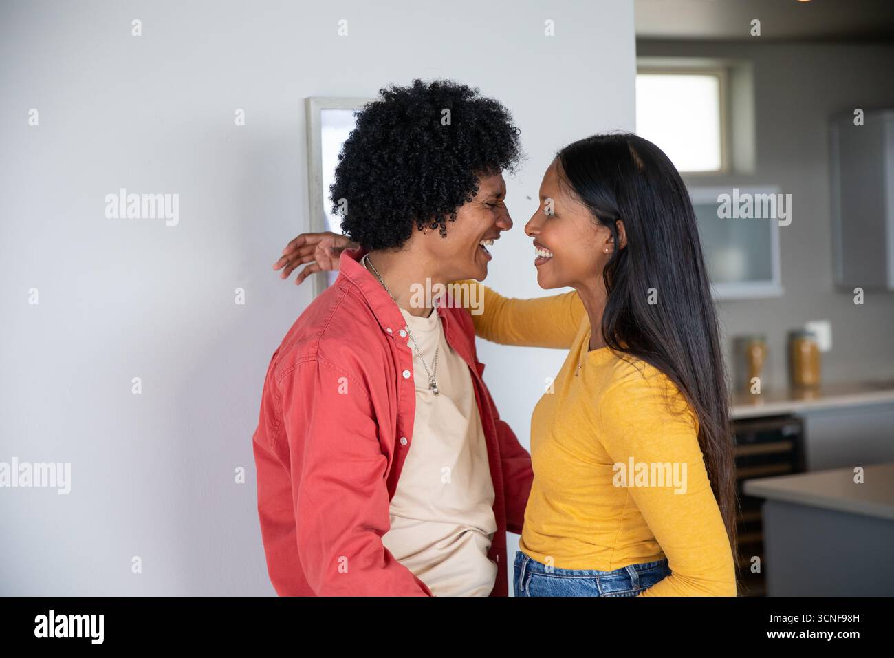 Couple diversifié debout à l'intérieur de la cuisine moderne de la maison se penchant l'un vers l'autre par des pots de stockage Banque D'Images Couple diversifié debout à l'intérieur de la cuisine moderne de la maison se penchant l'un vers l'autre par des pots de stockage Banque D'Images