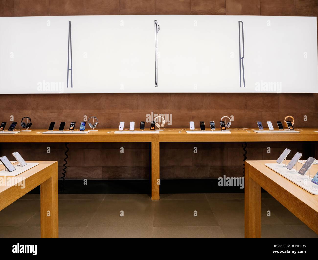 Paris, France - 19 septembre 2025 : L'intérieur d'un Apple Store présentant une grande bannière publicitaire pour l'iPhone Air, avec smartphones et écouteurs Banque D'Images