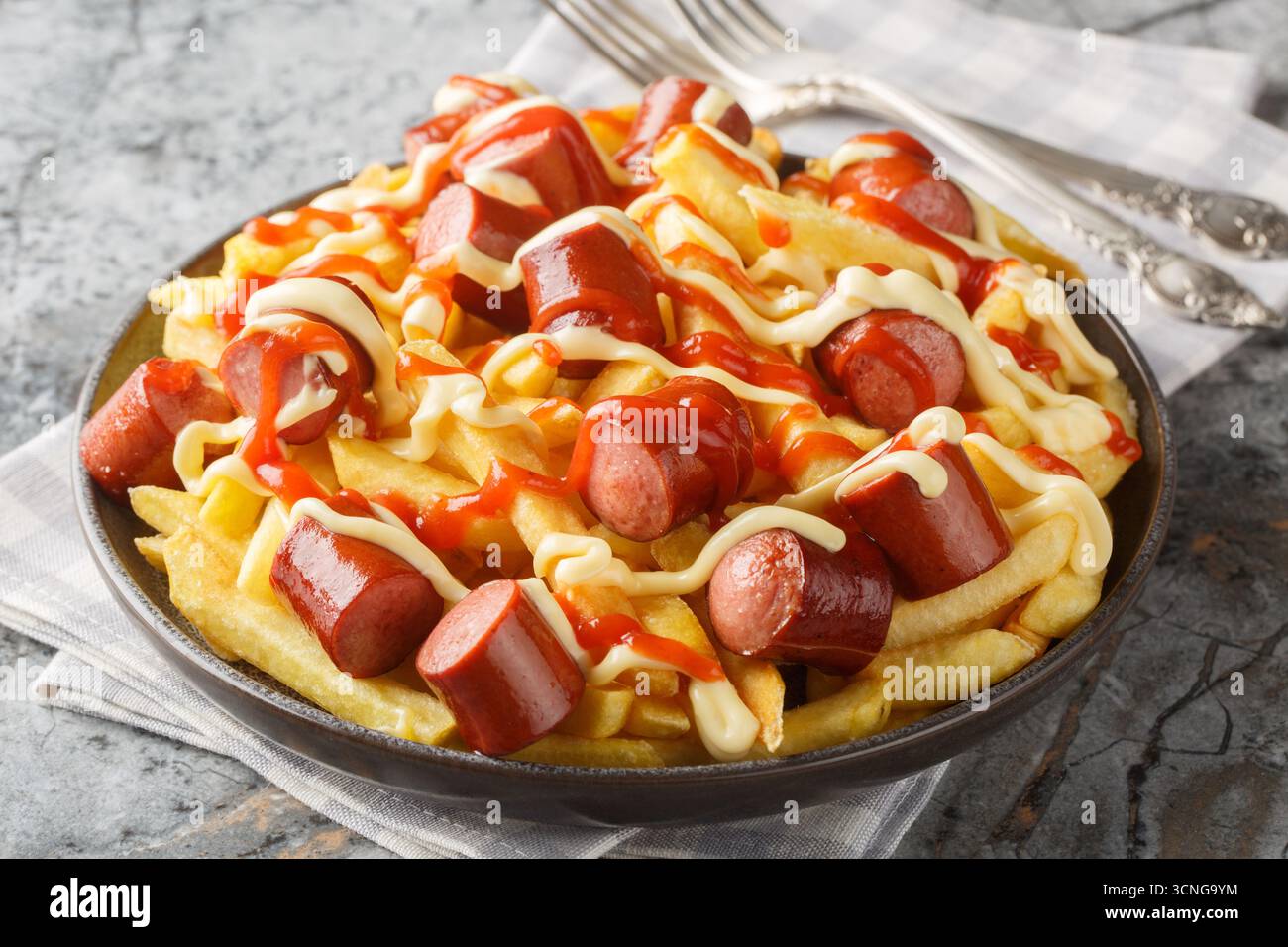 Salchipapas est un plat de restauration rapide sud-américain et caribéen composé de saucisses de bœuf poêlées finement tranchées et de frites en gros plan sur l'assiette Banque D'Images