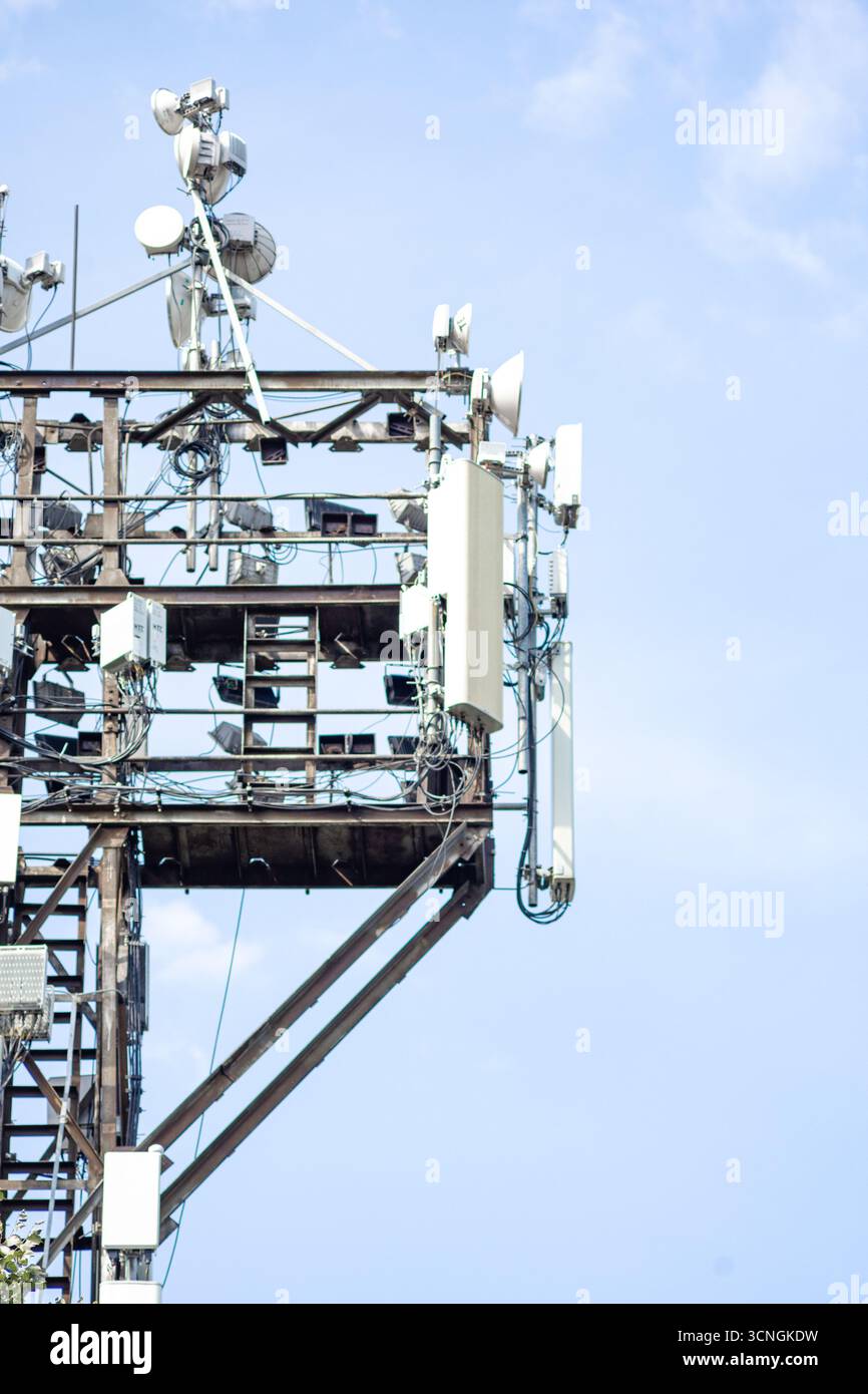 Tour cellulaire avec plusieurs antennes et antennes paraboliques contre le ciel bleu - infrastructure de communication moderne. Banque D'Images