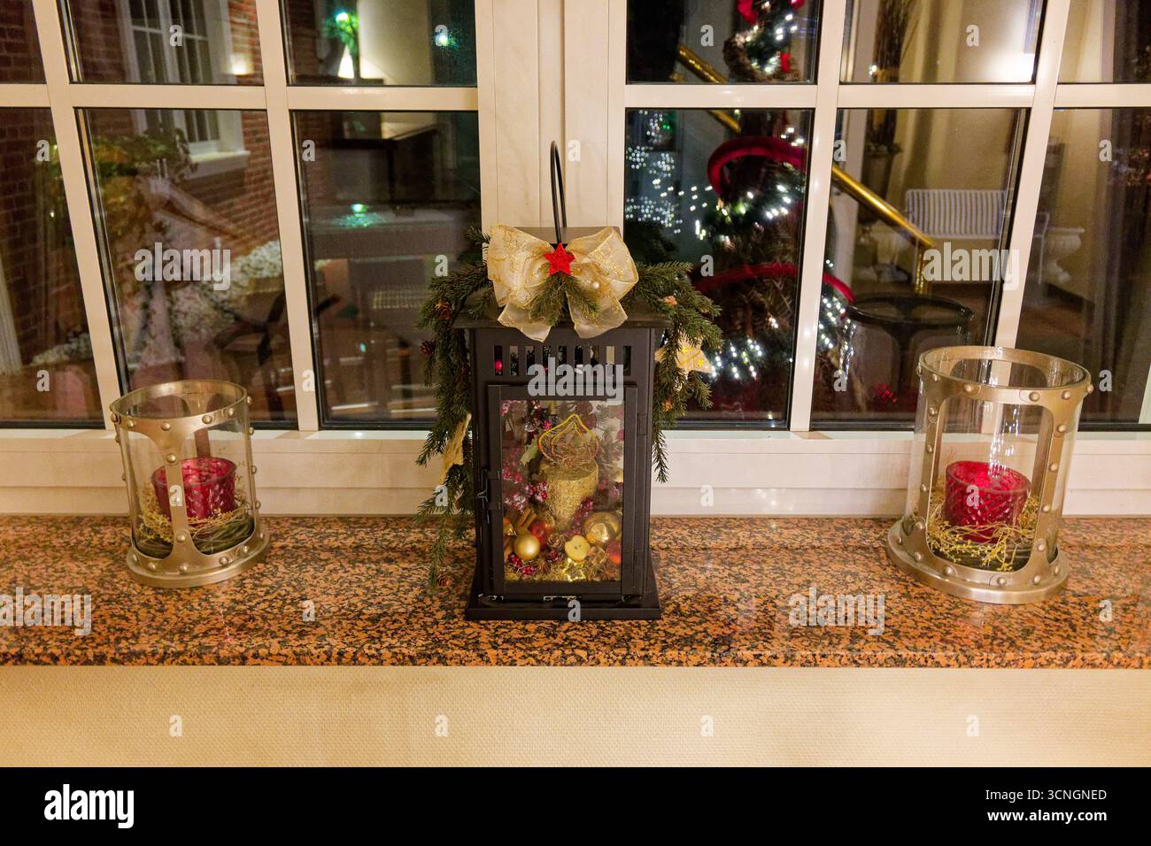 Sur un large seuil se tiennent trois bougies. Deux tasses en verre reposent dans des anneaux de foin, et une troisième repose dans une petite boîte de lanterne garnie d'arcs, d'ornements, d'un Banque D'Images