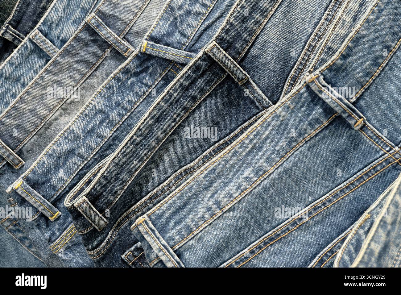Une pile de jeans bleus délavés en pierre, gros plan, fond abstrait de l'industrie textile Banque D'Images
