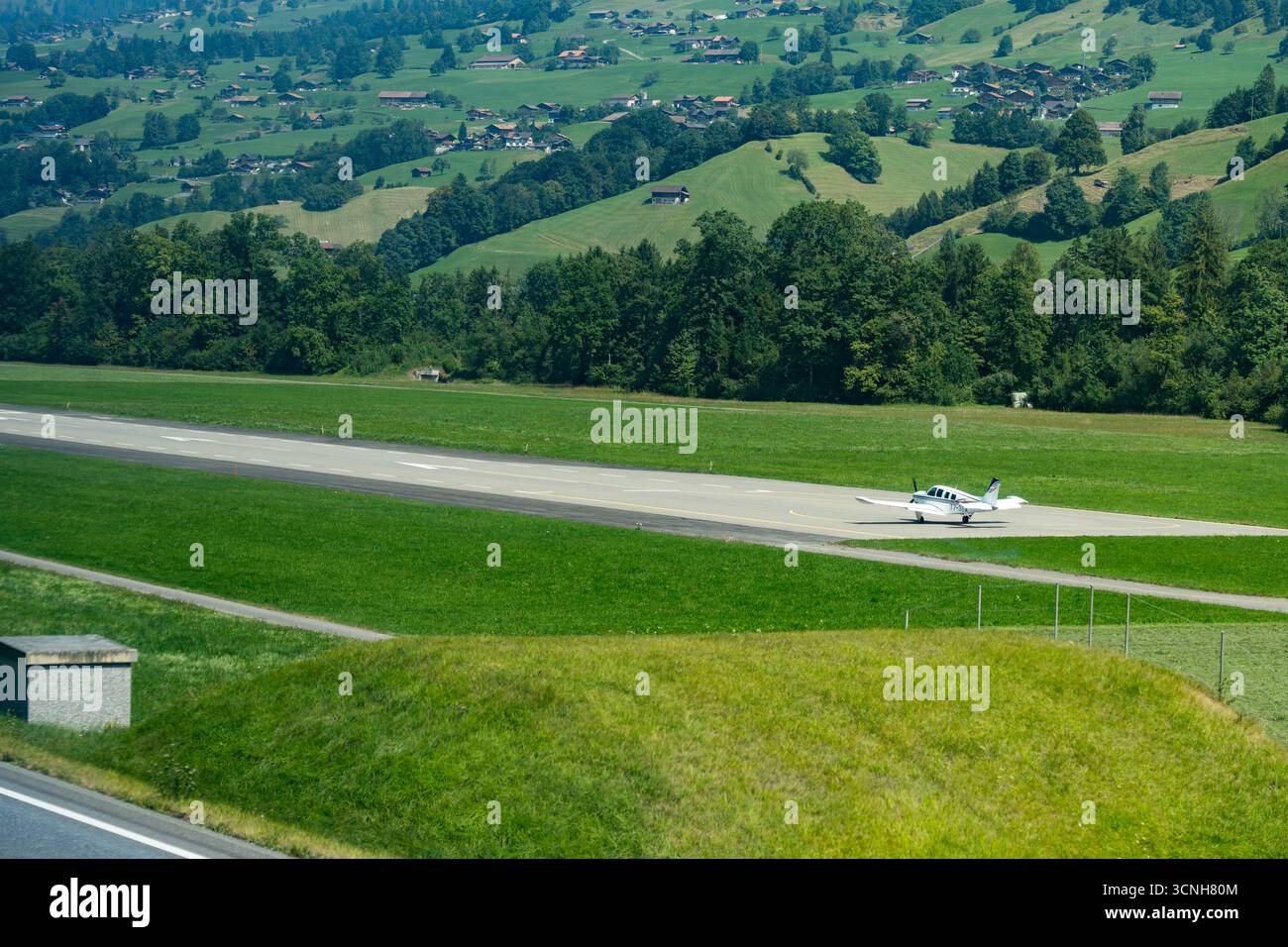 Petit avion Twin Otter sur un terrain d'herbe verte en Suisse prêt pour le décollage pris d'une fenêtre de train Banque D'Images