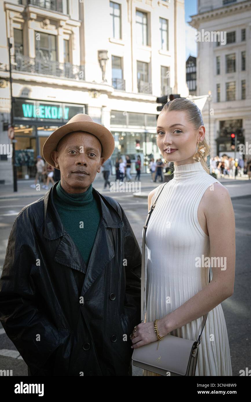 Un couple élégant qui présente la mode de rue pendant la Fashion week de Londres, posant dans une rue de la ville. Banque D'Images