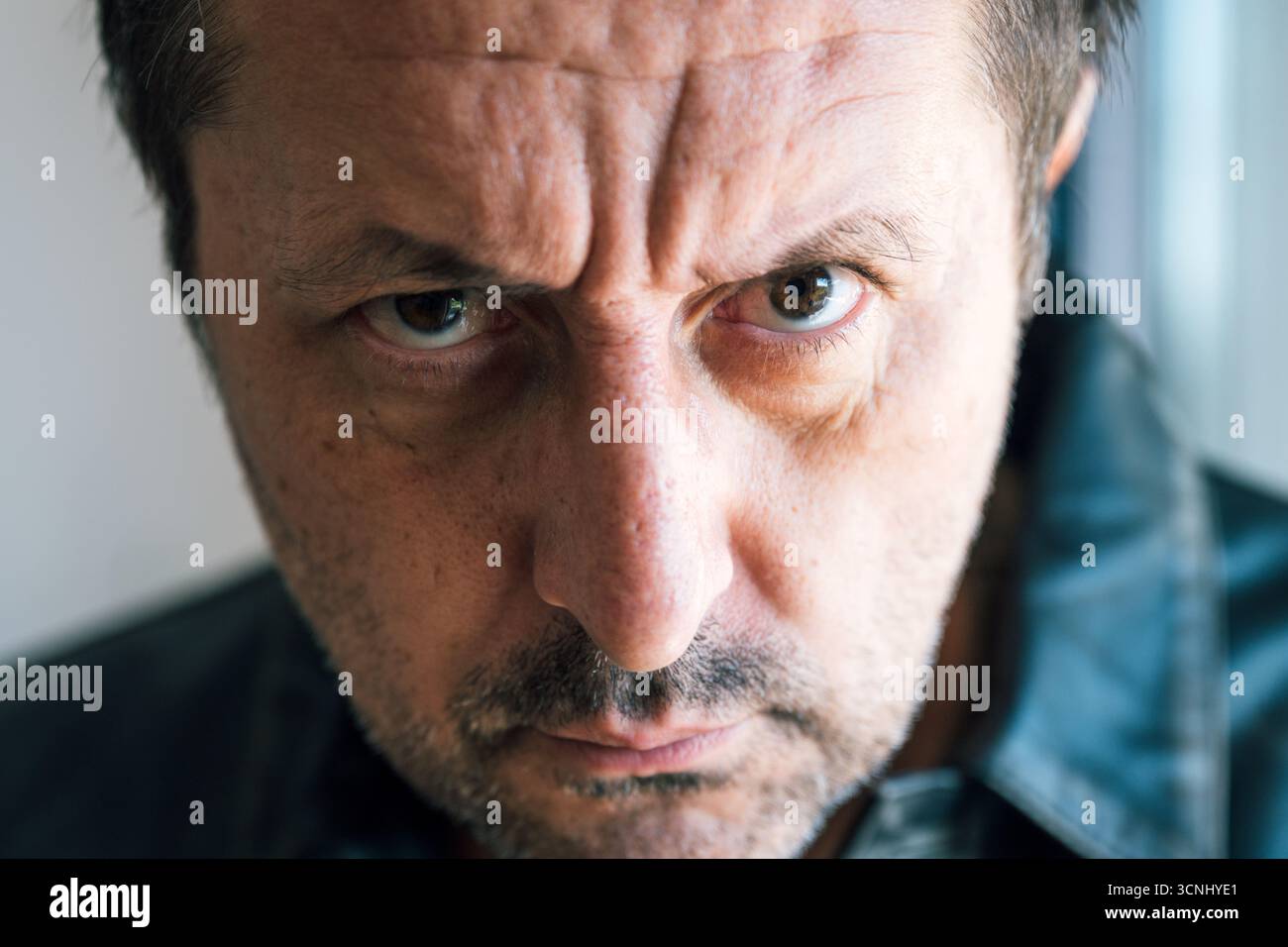 Portrait rapproché extrême d'un homme adulte mature montrant la colère avec une expression faciale tendue. Mise au point sélective. Banque D'Images