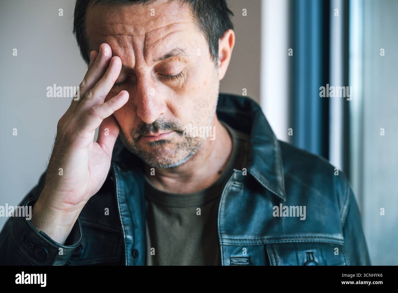 Homme adulte mature avec grimace douloureuse souffrant de céphalées de gueule de bois après avoir bu de l'alcool. Mise au point sélective. Banque D'Images