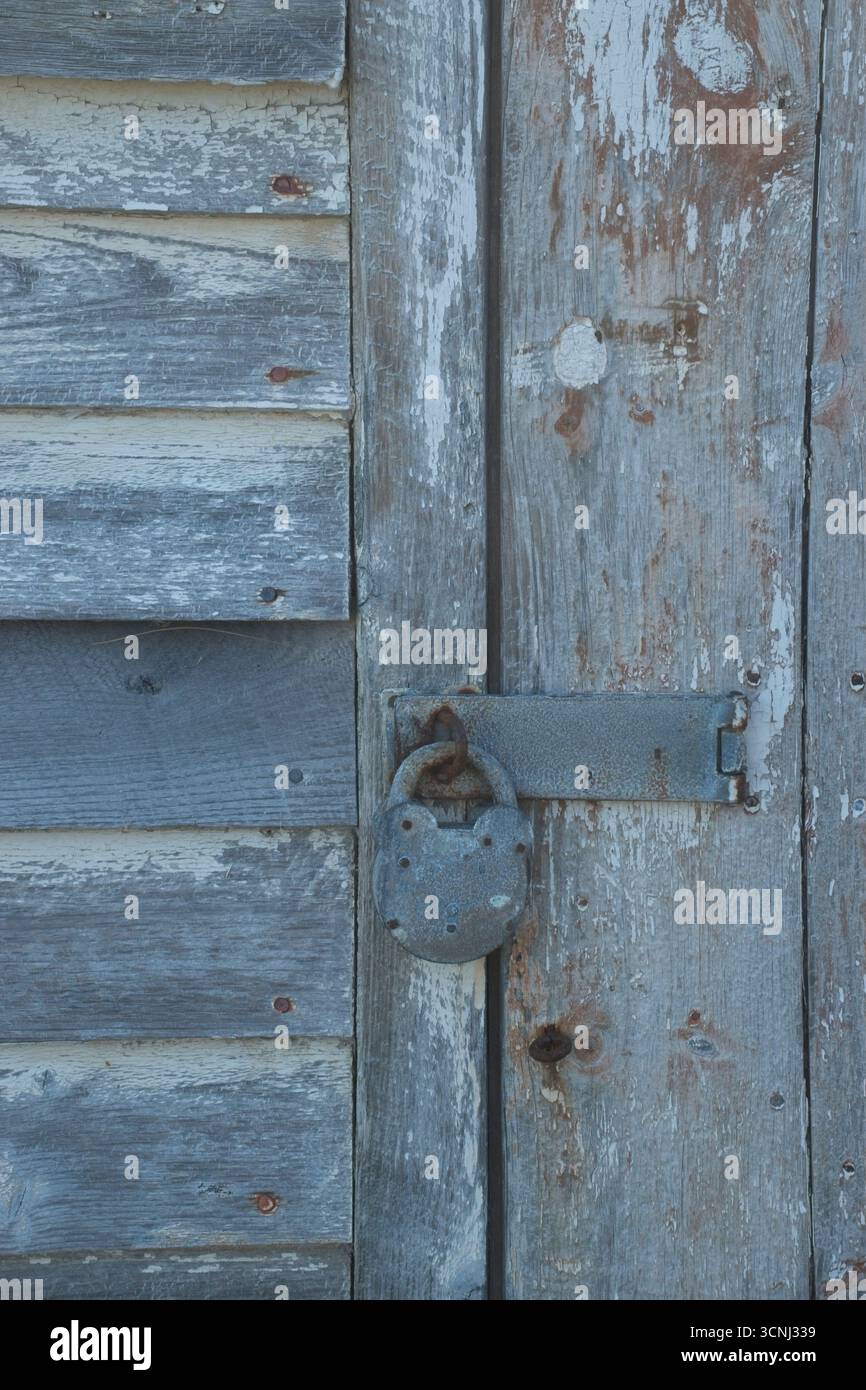 La porte en bois, peinte dans des tons de bleu et de gris, dispose d'une serrure rouillée, donnant un aperçu de l'histoire de cet endroit abandonné, mettant en évidence Banque D'Images