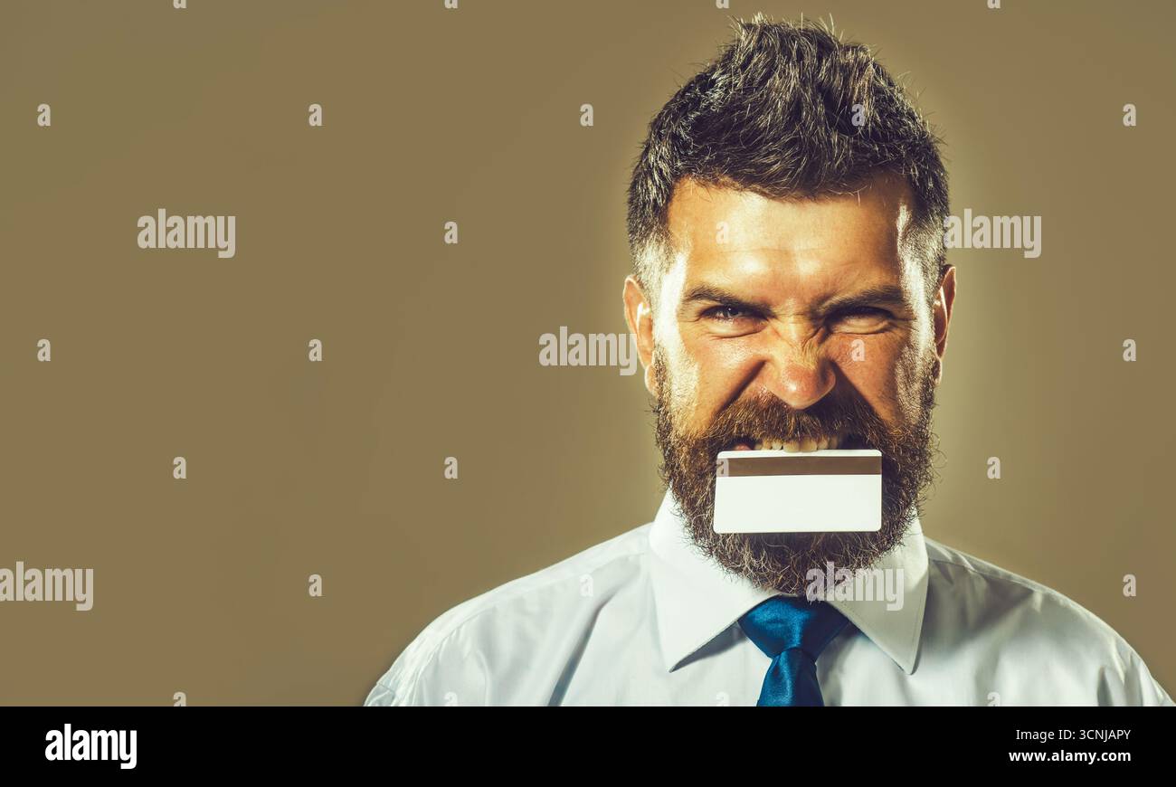 Bel homme d'affaires avec carte de crédit ou de débit dans les dents. Service bancaire. Carte bancaire à bande magnétique. Paiement sans espèces. Finance, paiement Banque D'Images