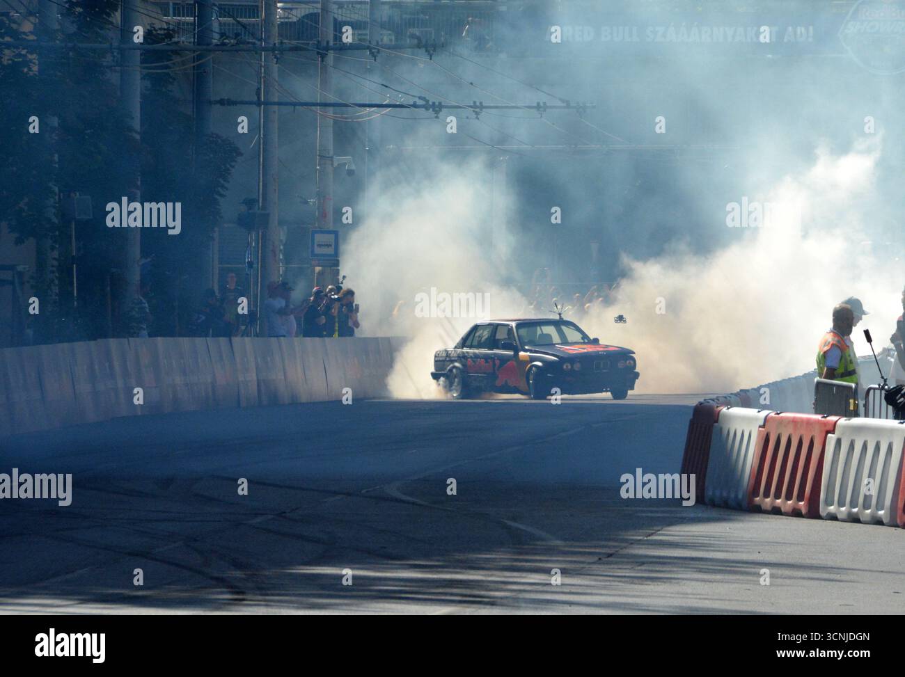 Sam Sam exécutant un impressionnant spectacle de dérive avec une BMW E30 325i à Budapest, produisant une fumée de pneu massive et divertissant la foule excitée Banque D'Images