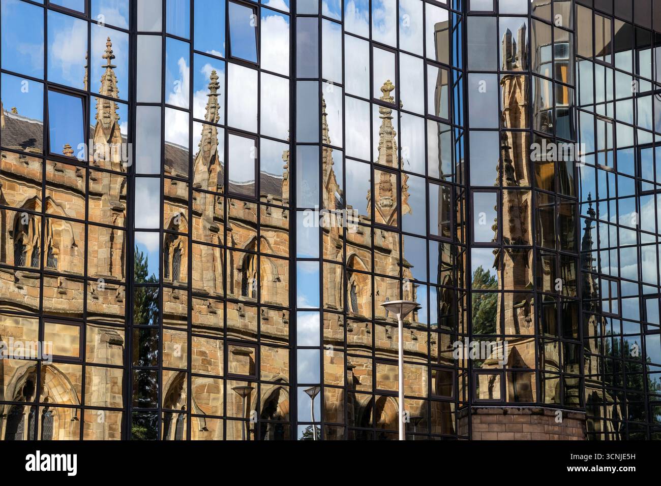 Une église traditionnelle reflétée dans la façade vitrée d'un bâtiment moderne à Glasgow Banque D'Images