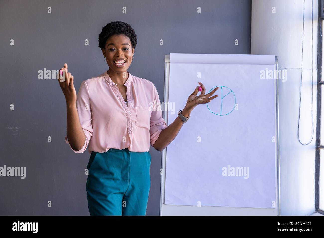 Femme afro-américaine présentant un graphique circulaire avec des marqueurs sur le tableau de conférence dans le bureau Banque D'Images
